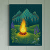 Paneled wood wall on a light teal color with canvas art featuring Firepit at night ,a twinkling starred sky and cascading mountains. Foliage along the side including ferns and wild lupine flowers
